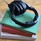 a small icon image of a pair of headphones on top of three stacked books